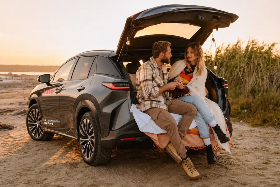 A couple by the open trunk of the Lexus RZ 450e at the beach