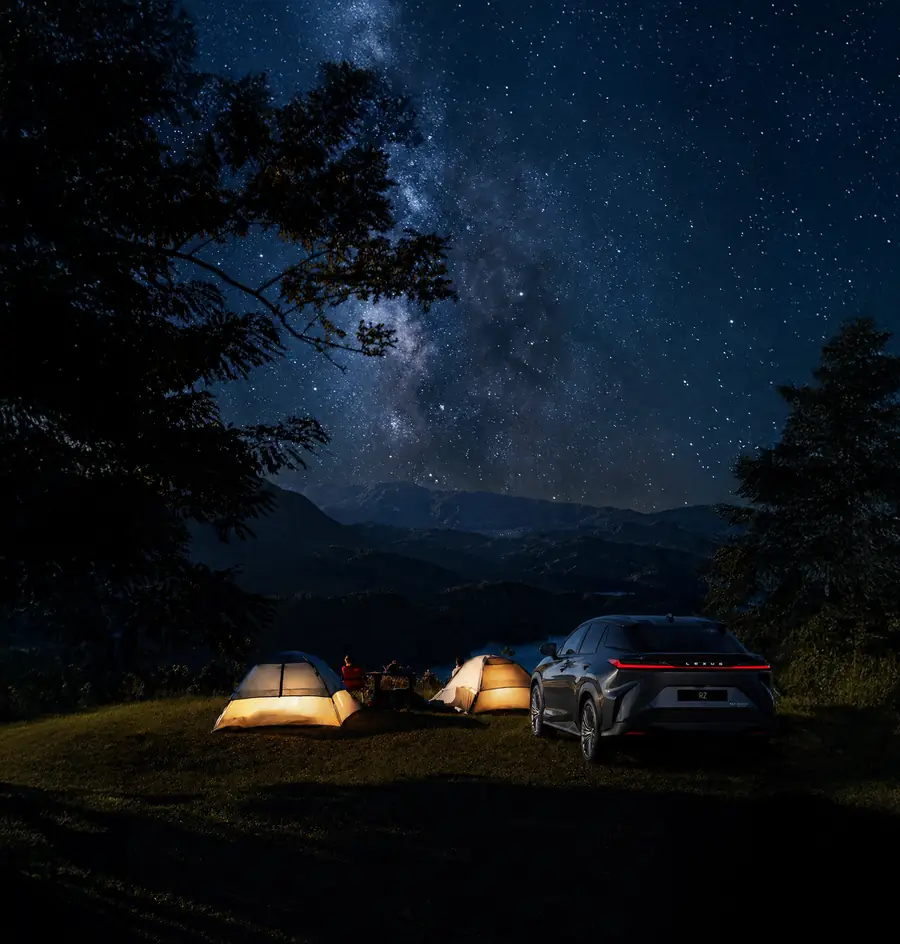 Tents pitched beside the Lexus RZ 450e under the stars
